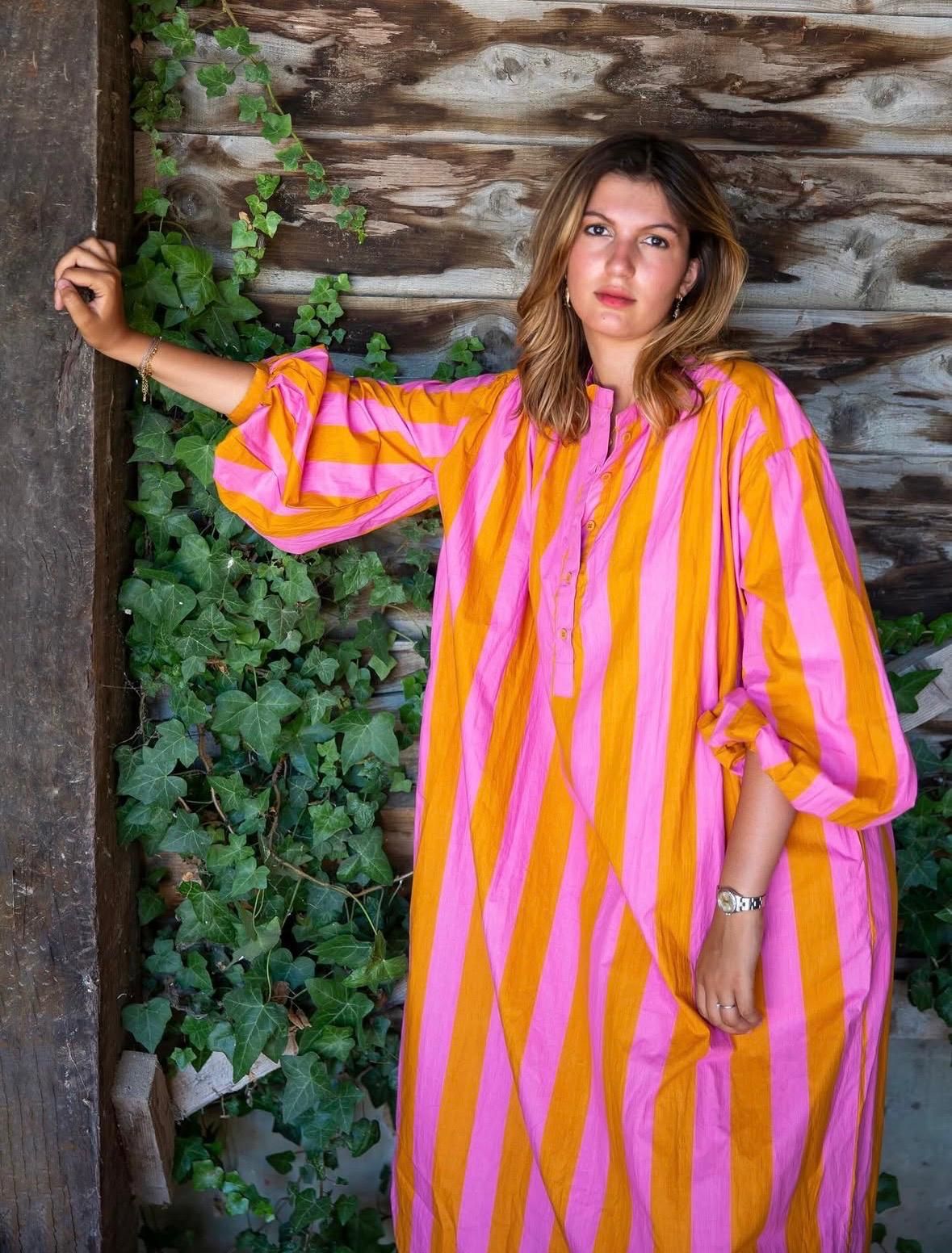 Favela Market — robe rayée rose et orange, mur de bois