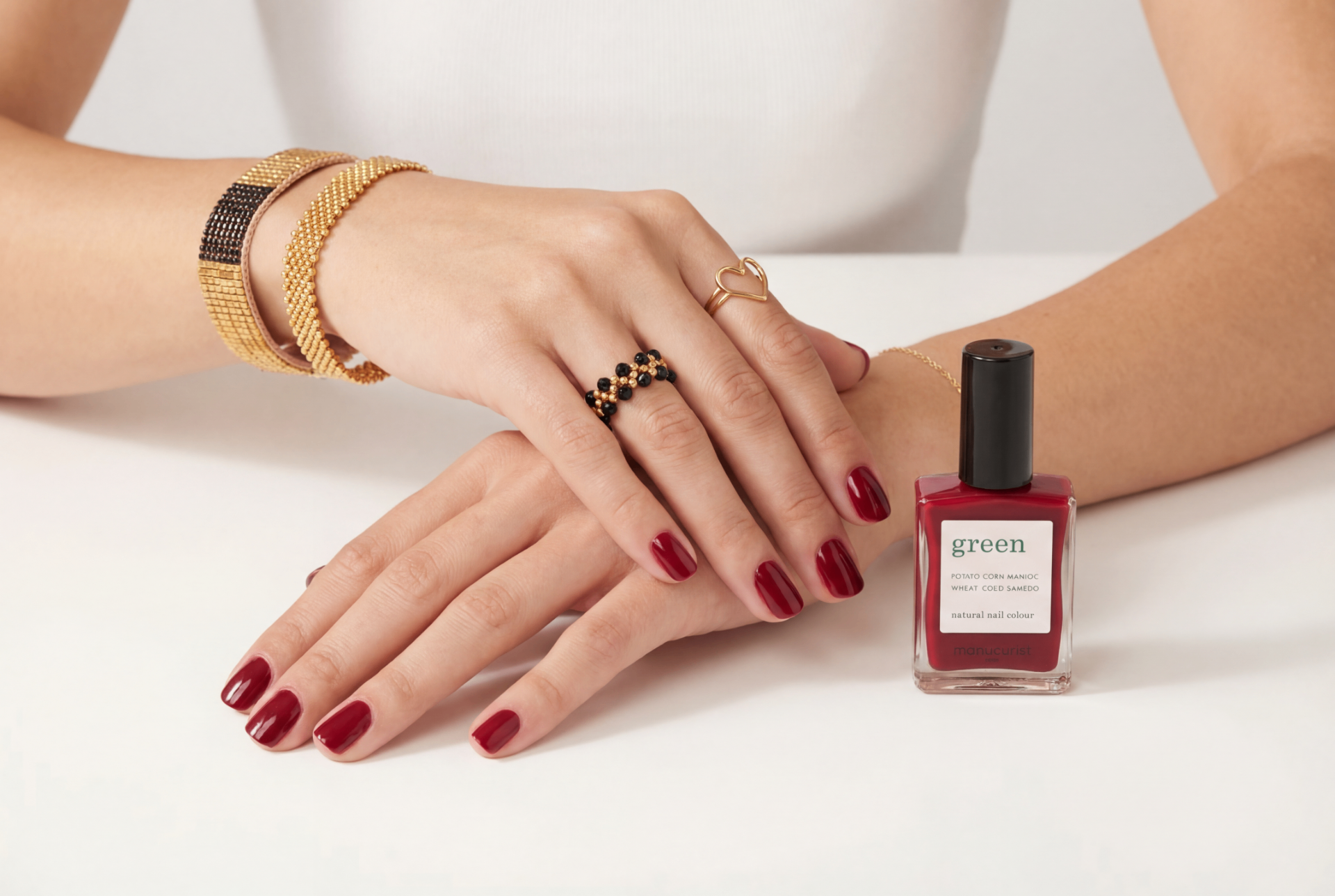 Ibu Jewels — manchettes tissées dorées, bague cœur et bague perles noires, mains au repos